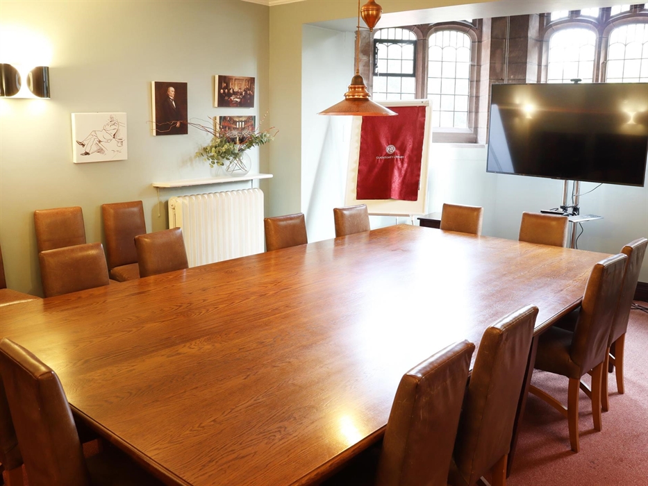 The Anwyl Room conference space. It can seat 12 people+ on comfortable leather chairs. There is a large wooden table in the middle and a TV screen at