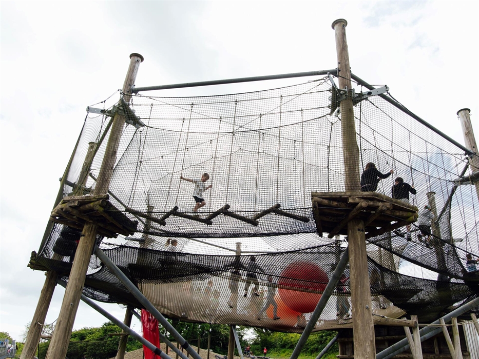 A huge adventure net with a netted trampoline in the centre