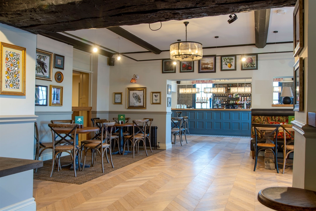 Tables and chairs with a bar in the background in a hotel bar and lounge.
