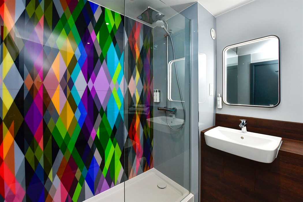 A shower cubicle and basin in a hotel room.