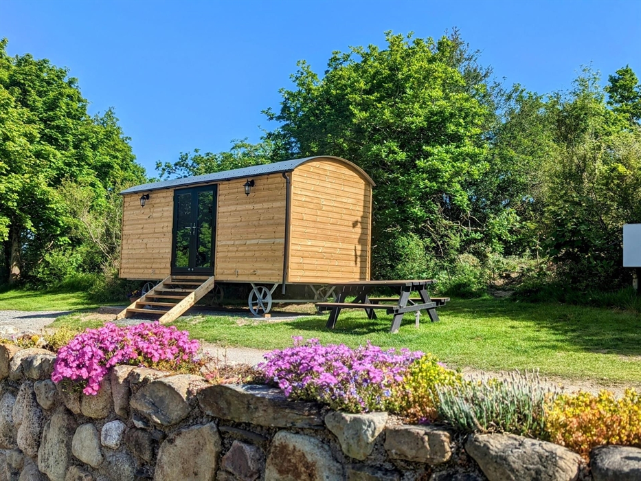 Shepherd Hut with picnic bench, trees and flowers