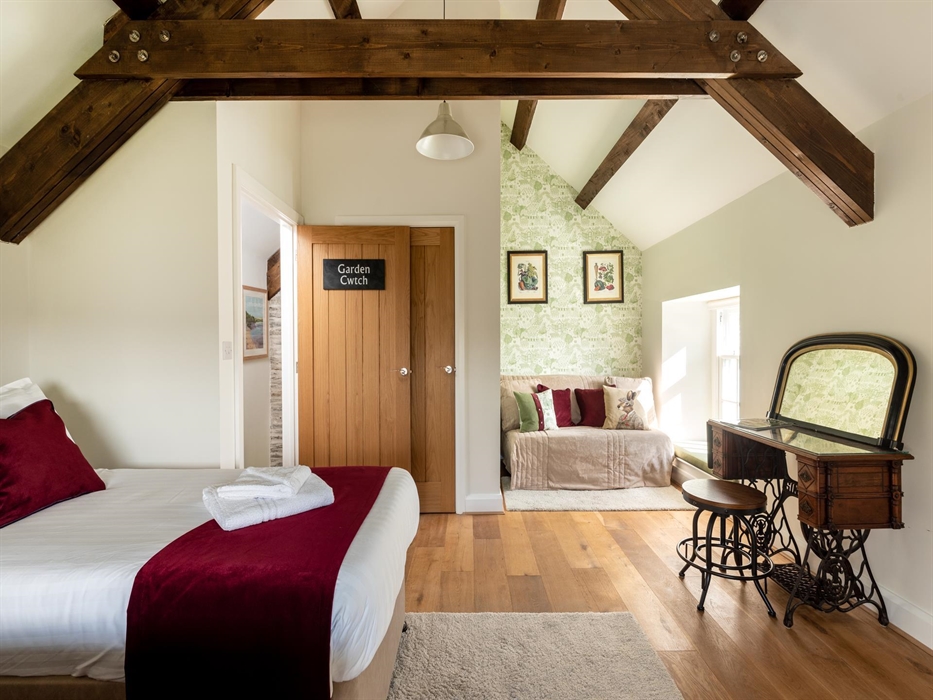 A double aspect huge bedroom with original oak beam ceilings, the front overlooks the garden to the Church and the other window towards the delightful