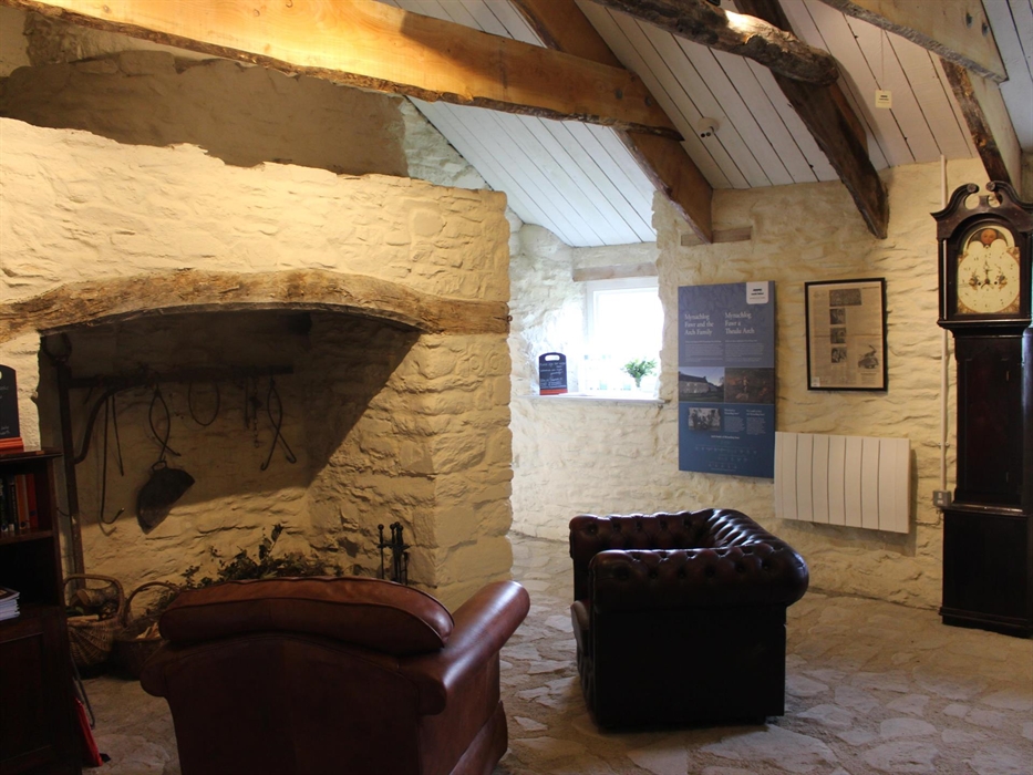 Two armchairs in front of a large fireplace with a grandfather clock in the background