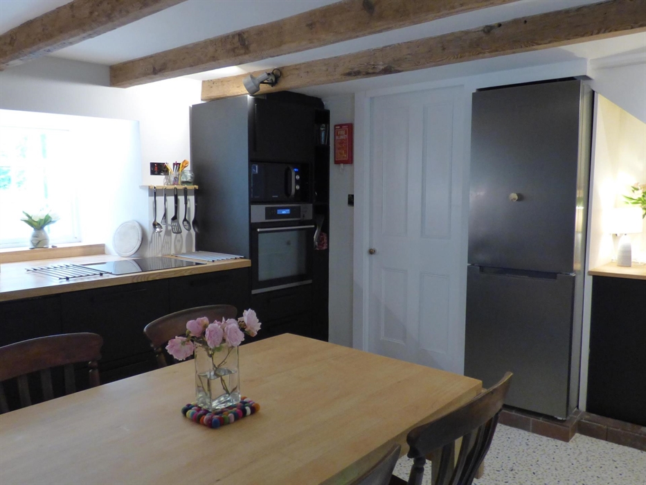 Kitchen Diner at Yr Hal Cottage, with dining table, modern kitchen fittings and a window looking onto the garden.
