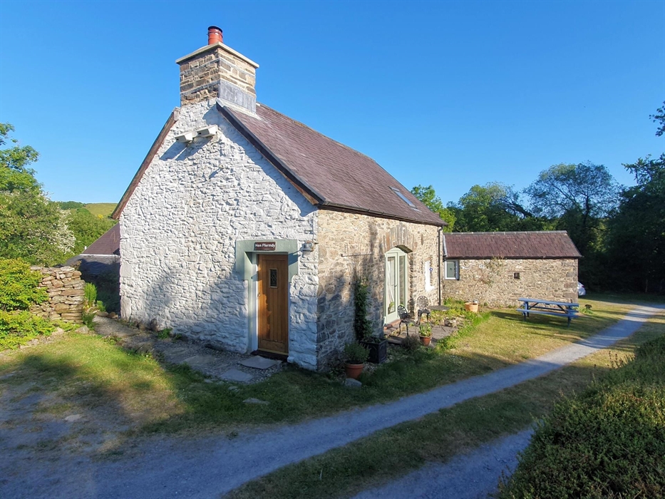Exterior view of Hen Ffermdy cottage with front small patio with table and chairs