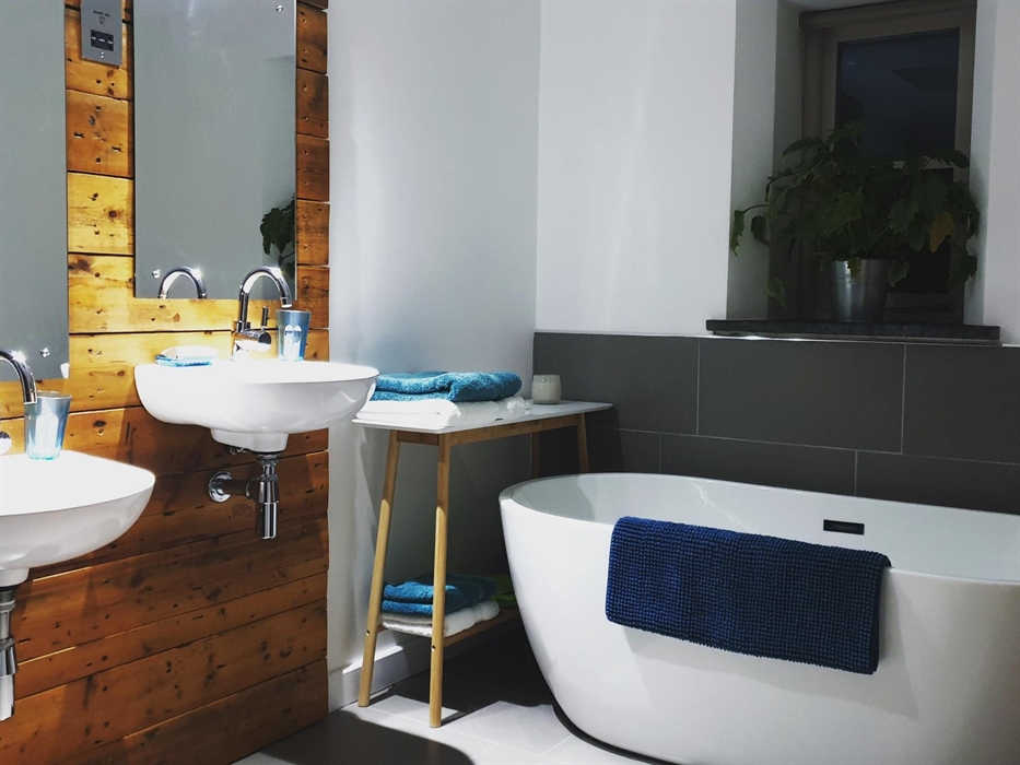 Accessible bathroom with high and low twin sinks, walk-in rainfall shower and freestanding bath tub.