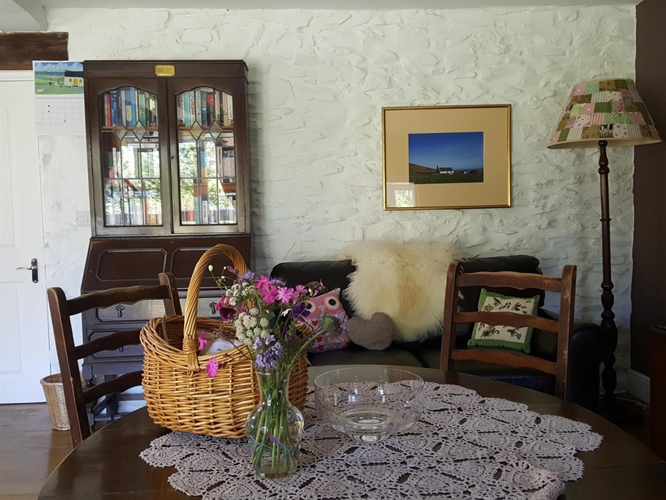 Hen Ffermdy cottage reading corner with sofa, sheepskin throw and cabinet full of books