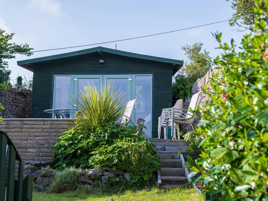 To the rear of the cottage, there is a garden, with a lawn and patio and a summerhouse.  On the patio, there is dining furniture and inside the summer