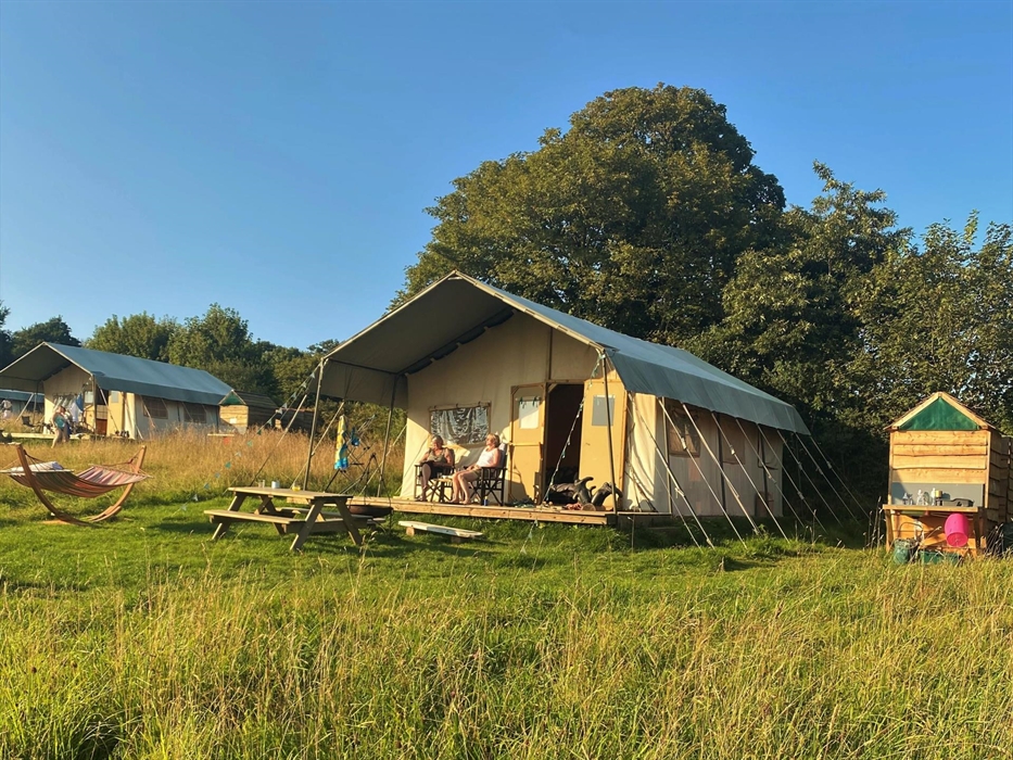 A large canvas glamping tent where you can enjoy overlooking the meadow, have a fire in the firepit or hang out in the hammock.