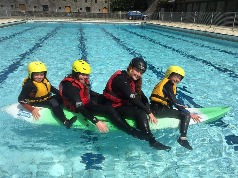 Children sat on kayak in outdoor swimming pool of St Donat's Castle