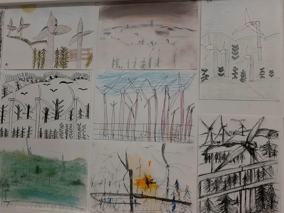 Eight drawings on a wall tightly arranged. All depict wind turbines but in varying styles and colours. Some are outline black and white whereas others