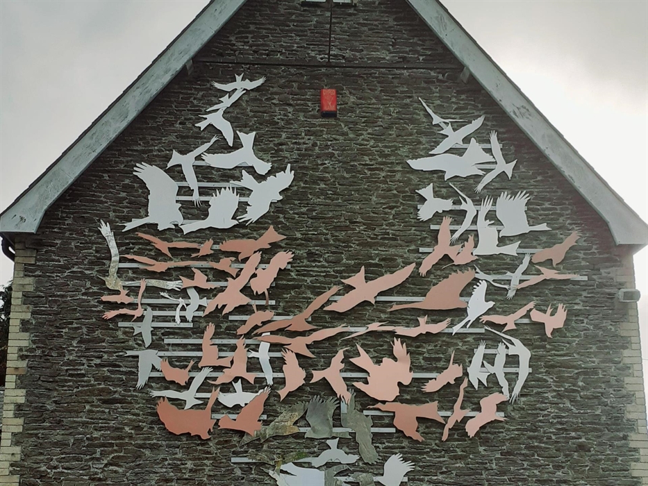 Gwaith celf yr artist Ted Harrison 'Erlidigaeth yn Troi'n Ddathliad'  yn dathlu goroesiad y barcud coch a'r iaith Gymraeg. Celebrating the survival of