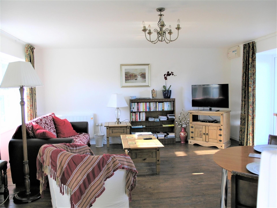 Spacious open plan lounge/dining/kitchen with large front window and patio doors.