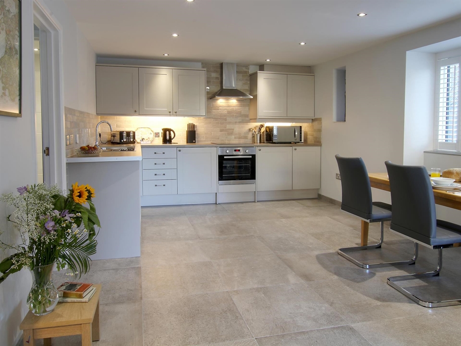 Well-equipped kitchen with pale cabinetry, integrated appliances, and a large dining table set for breakfast.
