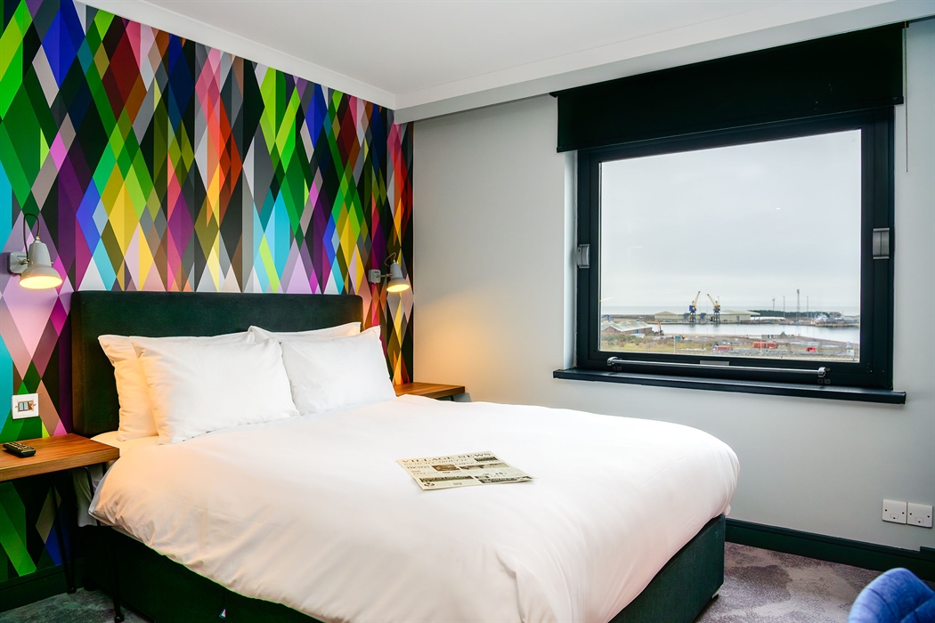 Double bed in a hotel room with views toward the bay