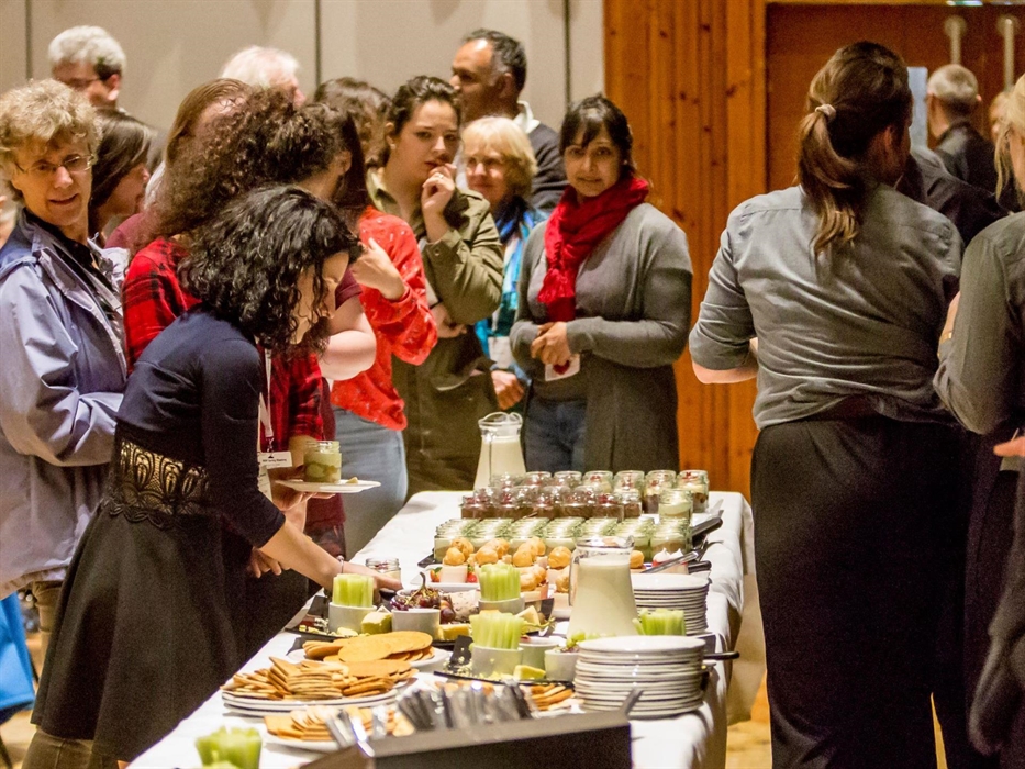 Delegates getting food from a self-serivce buffet of cheese and desserts.