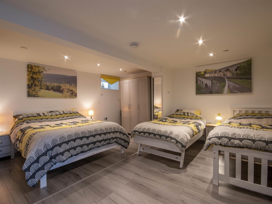 Welsh Row House Family Bedroom. Mirror, bedside cabinets and lamps. Wardrobe and laminate floor. Baby Travel Cot.  Room sleeps up to four (Not includi