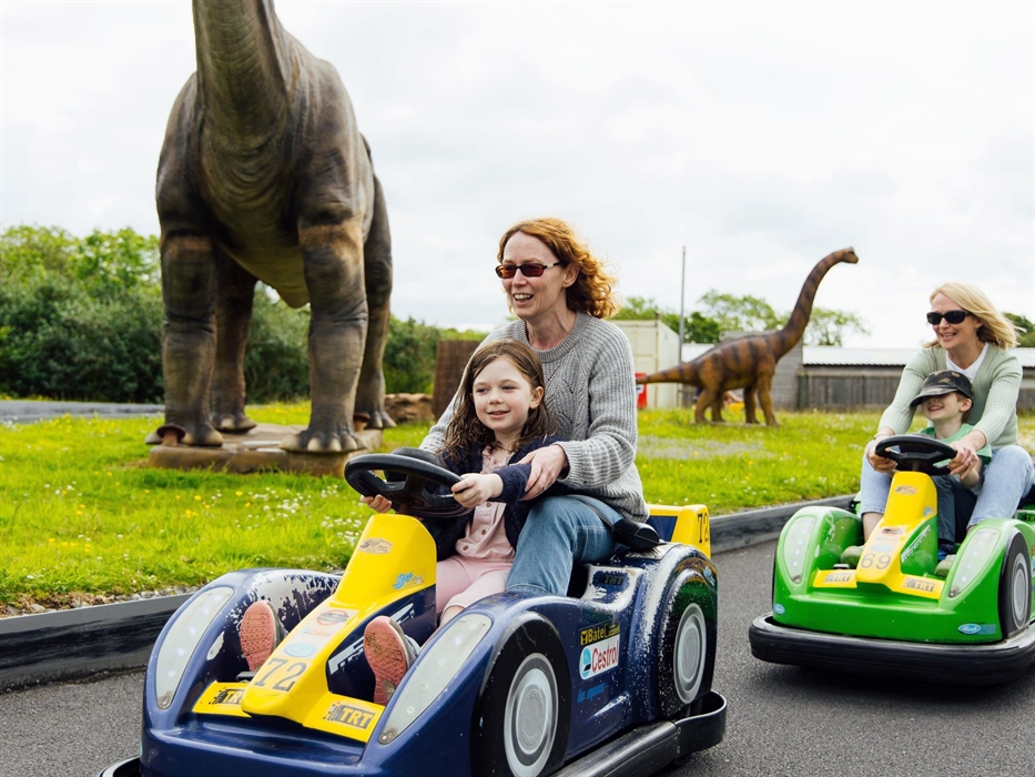 Two mums with their children, each on a go-kart, racing each other on the race track.