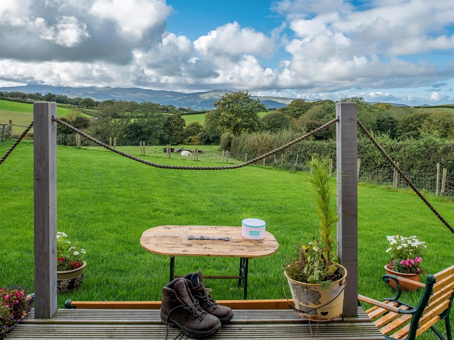 The hut looks out past the paddock, over the farm fields, and on to the Carneddau mountains beyond.  There are cows and trees and it is very green.