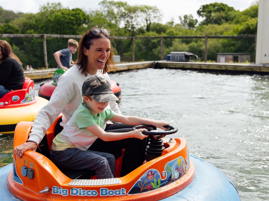 A mother and son having fun on the big disco boats, which are being driven on water.