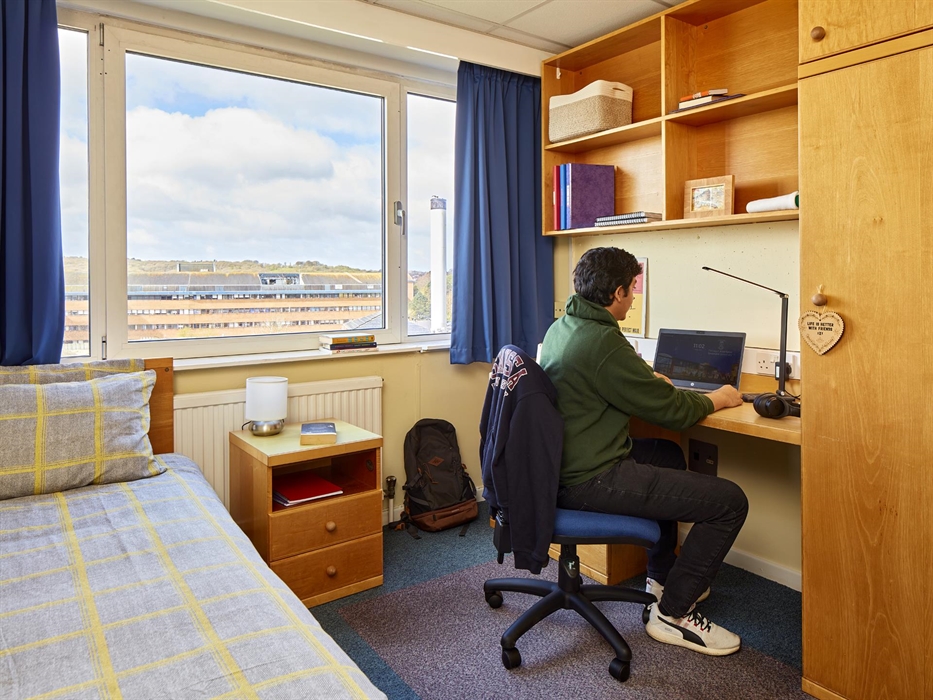 Student using laptop in a bedroom on singleton campus
