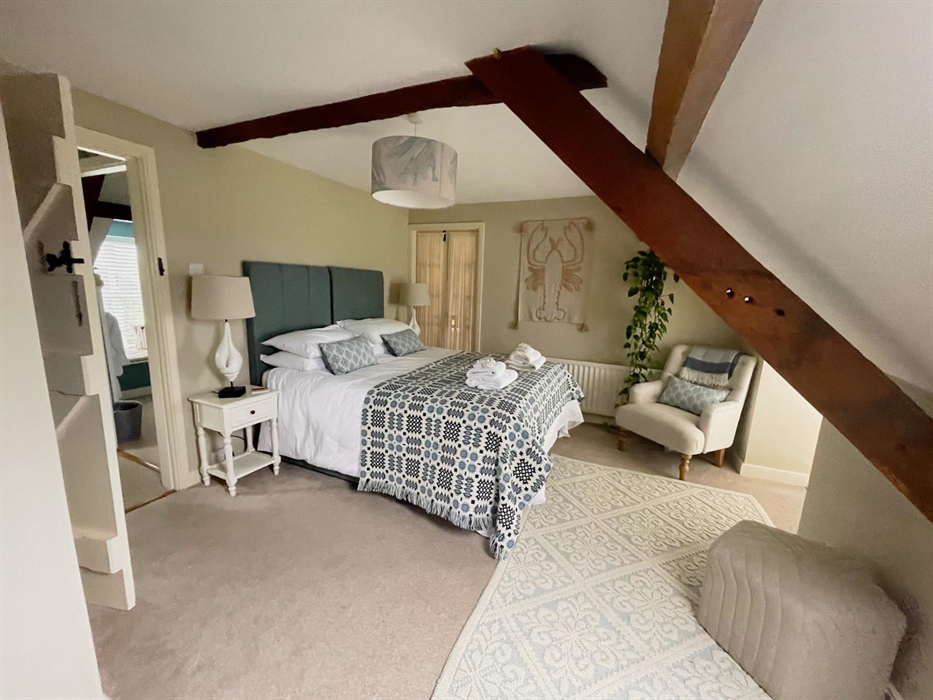 Kingsize bedroom at Seadog and Stone Ysgubor Degwm with white linens and a welsh tapestry throw in blues. Lobster wall art.