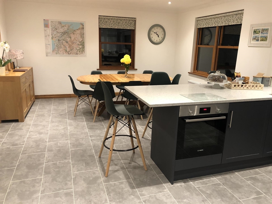 Kitchen with table and eight chairs, sideboard, breakfast bar with three high chairs.