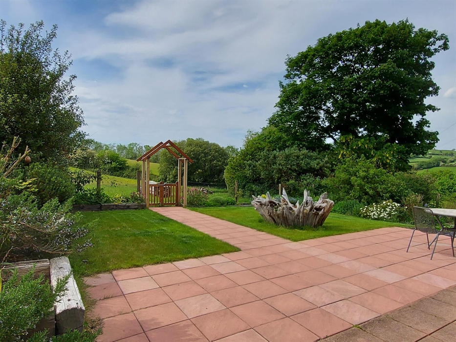 Spacious patio and maturing gardens with stunning views beyond. Through the arched gate leads to the glorious meadow and view of Cardigan Bay and the