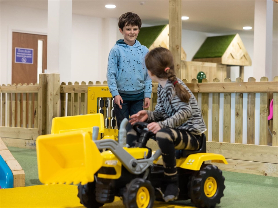 kids playing on tractors in play barn