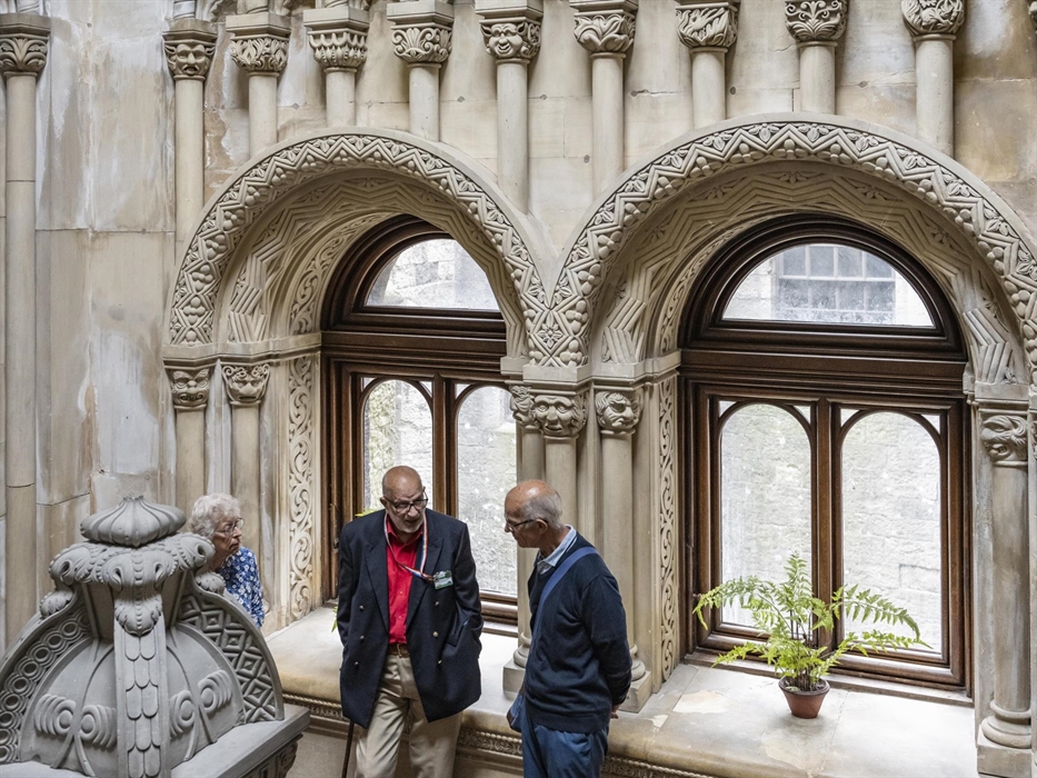 Volunteer talking to visitors on the carved Grand Staircase at Penrhyn Castle