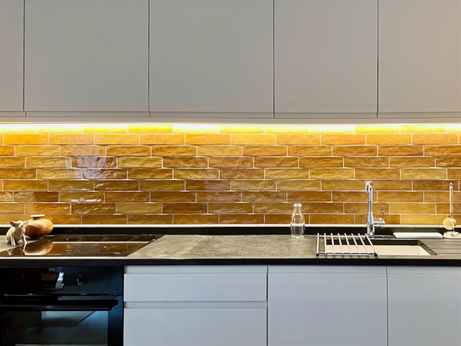 The kitchen has natural slate worktops, simple contemporary cupboards and brightly coloured tiled splash back