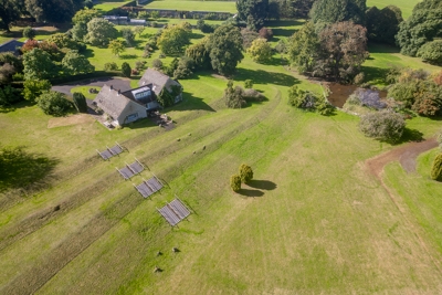 birds-eye view of The Glanusk Lodge at Glanusk Estate surrounded by beautiful parkland with gardens and trees surrounding it on a sunny day