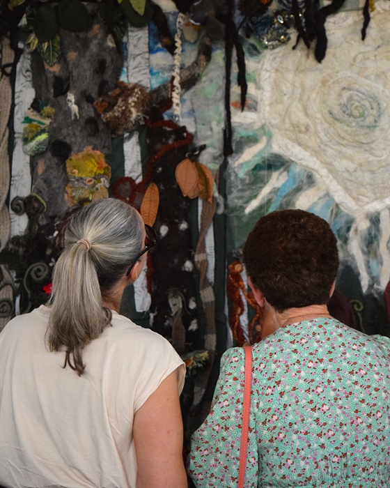 Two women admiring artwork in the gallery. The picture is of the back of their head.