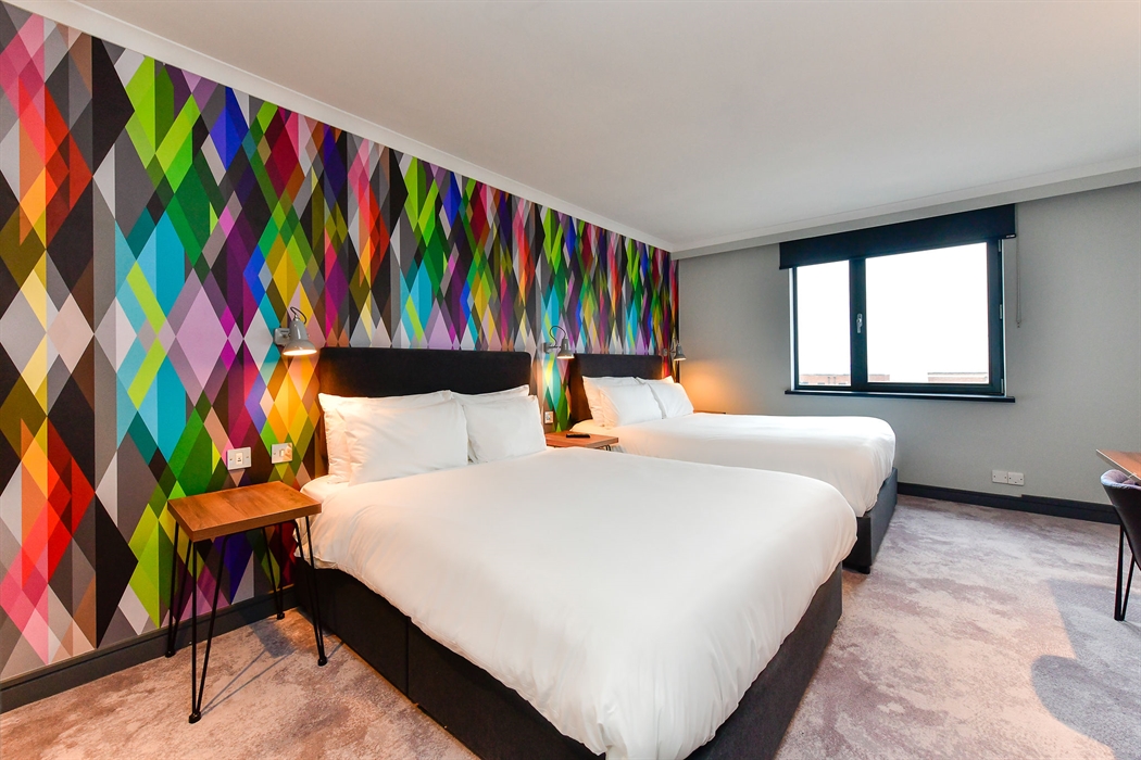 Two double beds in a hotel room with views out toward the bay