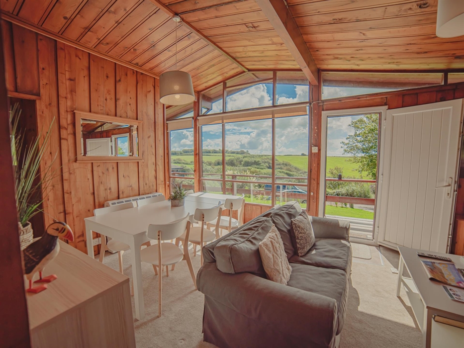 Bright, cosy interior of the lodge's main living area, inviting warmth with a stunning vista of the Timber Hill valley unfolding through the expansive