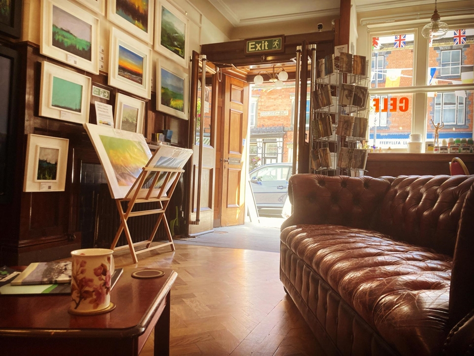 Framed original painting, a red Chesterfield sofa and an open door.