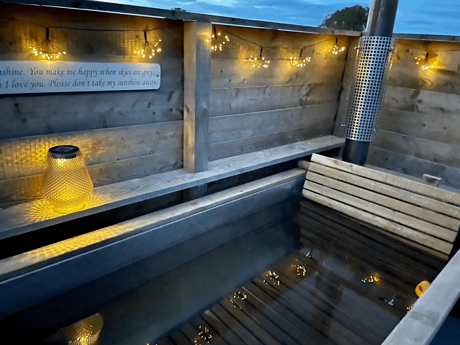 Hot tub at night with twinkling lights and bath filled complete with rubber duck