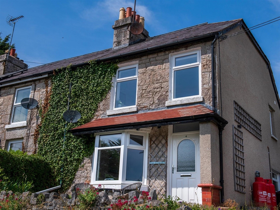 The front of the cottage, there is a driveway with parking on the right