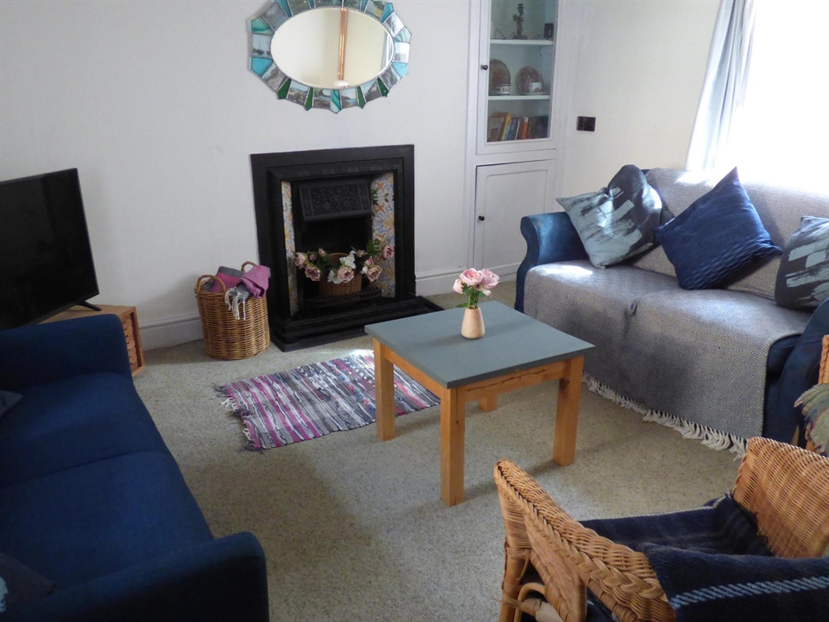 Yr Hal sitting room with sofas, TV and original features.