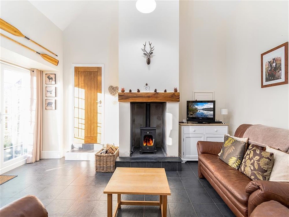 The Barns living area with seating for 4 people, TV, log burner and the door leads out to a decking area.