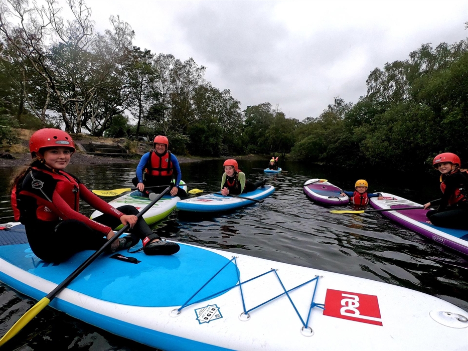 A group of paddleboarders sitting together on their boards.