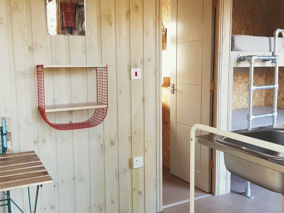 the inside of a wooden cabin with a door and beds