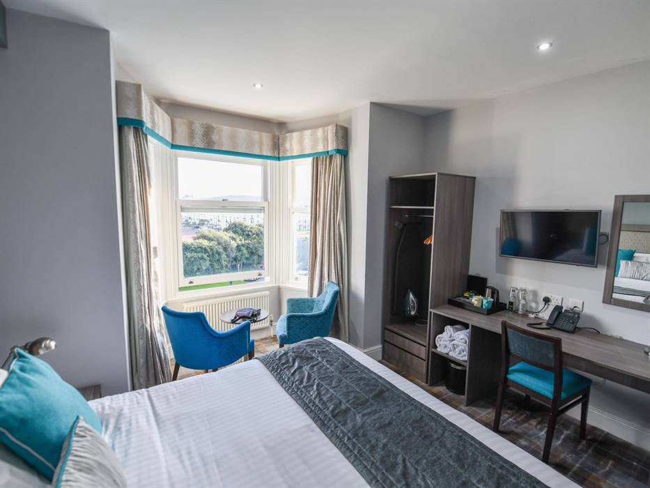 A bright and stylish hotel room with a comfy bed, sleek workspace, and a scenic window-side lounge!