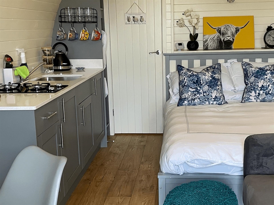 Showing inside of the luxury glamping pod with bed, sofa and kitchenette
