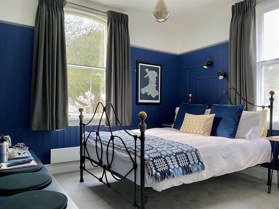 A bed with a blue and white Welsh blanket in a guest bedroom at Crafnant House