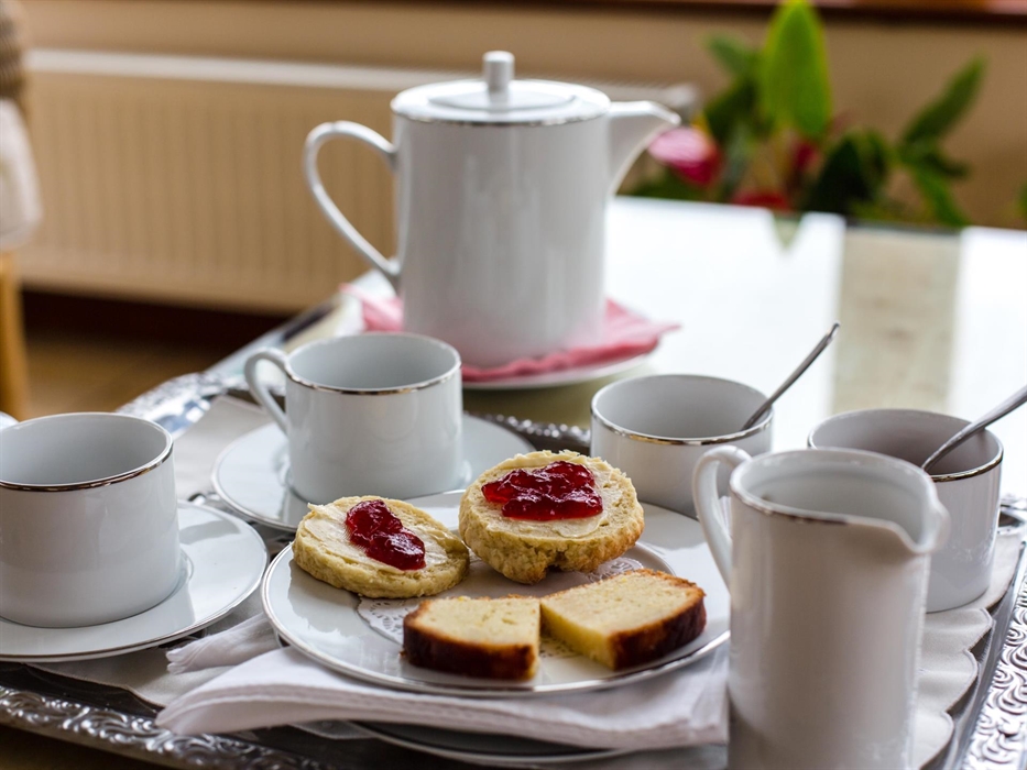 Afternoon tea;teapot, two cups sugar b owls, milk jug, scones and lemon drizzle cake.