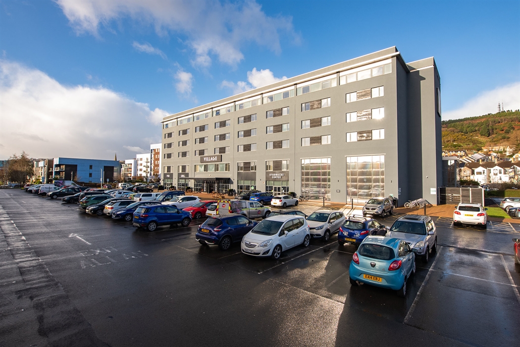 Exterior shot of a hotel and its car park.