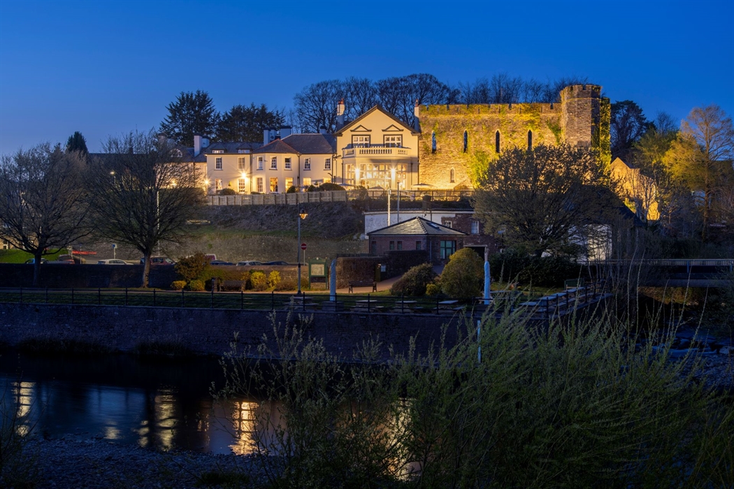 Exterior shot of a hotel at night next to a river.