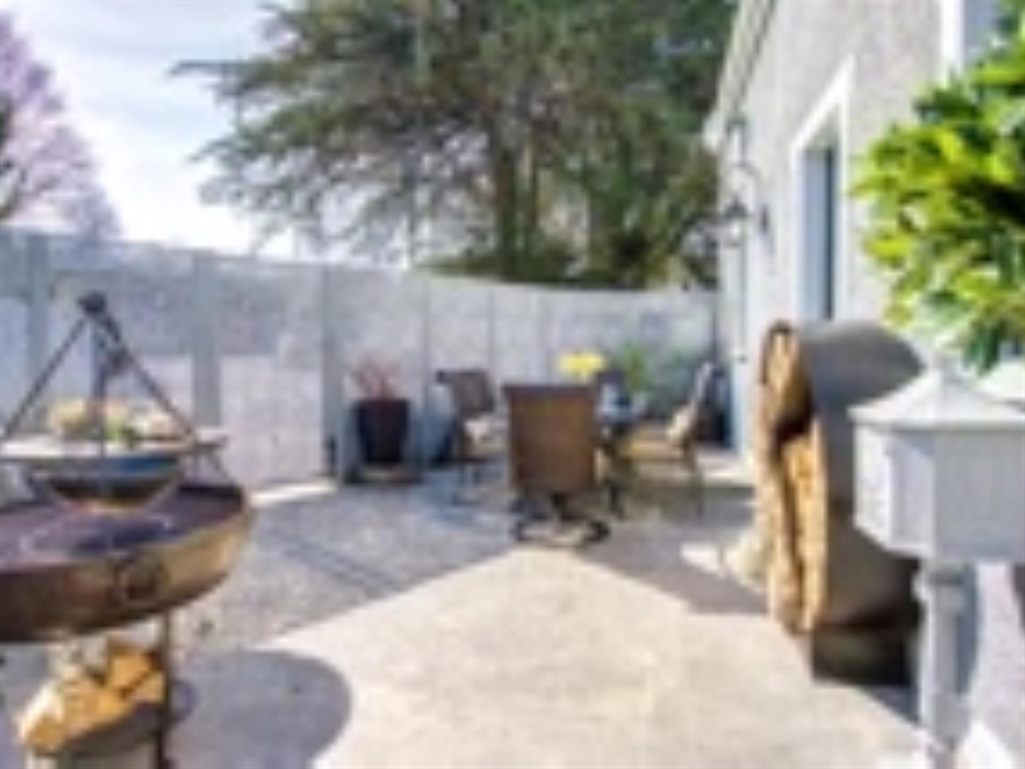 Private patio area containing Kadai, firepit, pizza oven, log store and dining table