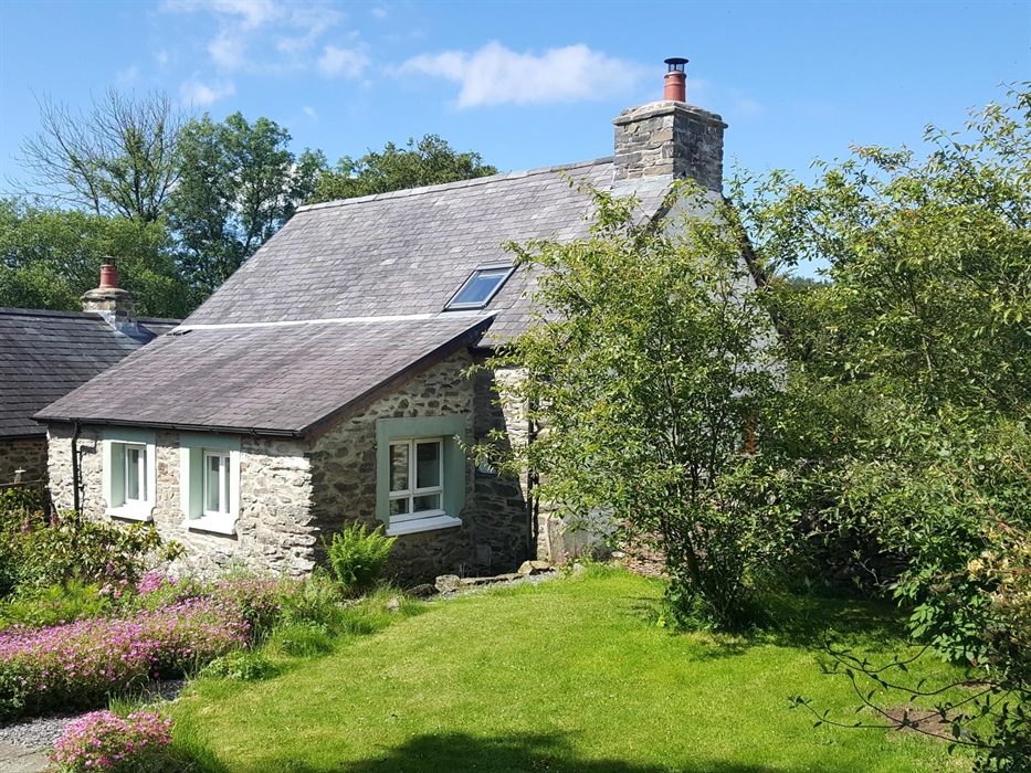 Rear view of Hen Ffermdy cottage with overlooking kitchen windows and rear garden with lawn